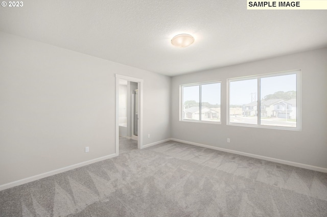 carpeted empty room with baseboards and a textured ceiling