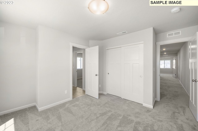 unfurnished bedroom with carpet floors, baseboards, and visible vents