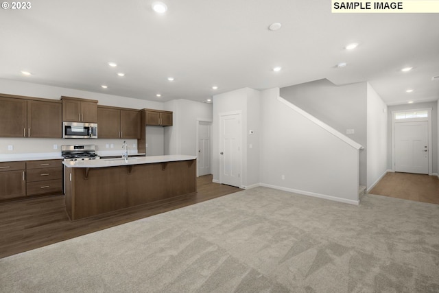 kitchen featuring stainless steel appliances, recessed lighting, light countertops, a kitchen island with sink, and a sink