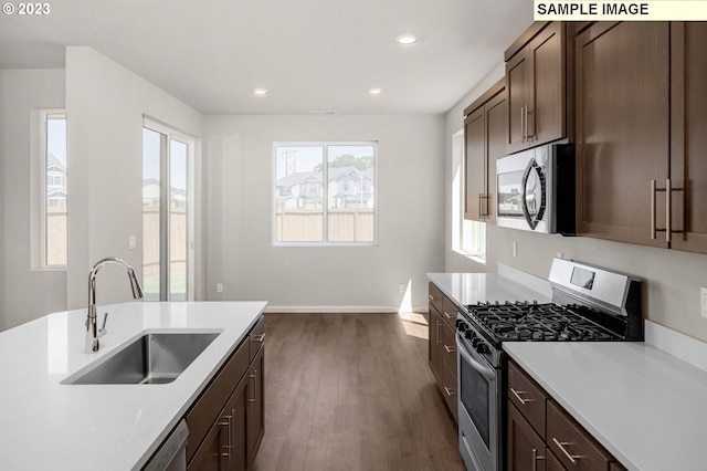 kitchen with dark wood finished floors, recessed lighting, light countertops, appliances with stainless steel finishes, and a sink