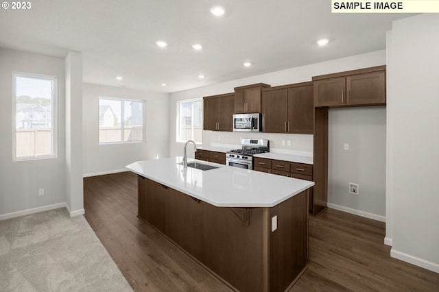 kitchen with appliances with stainless steel finishes, a sink, a center island with sink, and recessed lighting