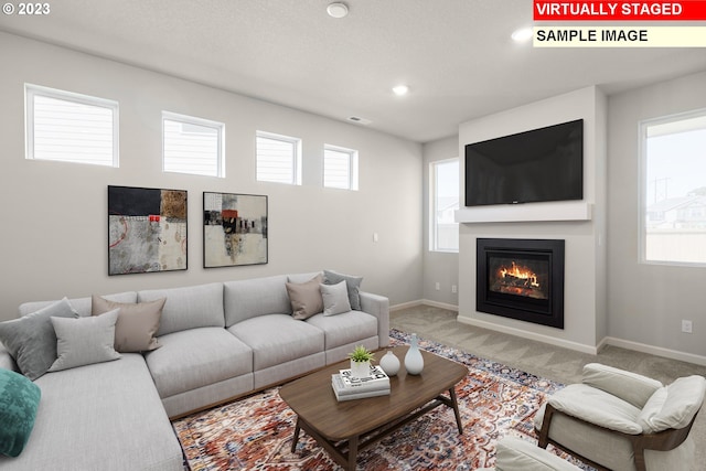 carpeted living room featuring recessed lighting, baseboards, visible vents, and a glass covered fireplace