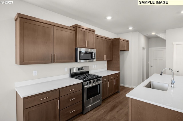 kitchen with recessed lighting, a sink, light countertops, appliances with stainless steel finishes, and dark wood finished floors