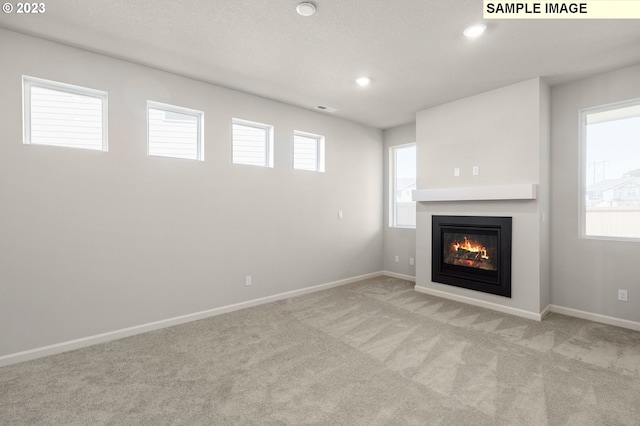 unfurnished living room featuring carpet, a healthy amount of sunlight, visible vents, and recessed lighting