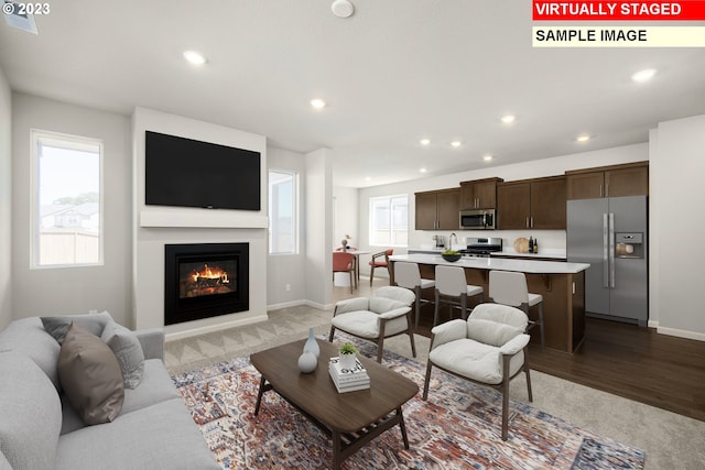 living area with recessed lighting, a glass covered fireplace, and baseboards