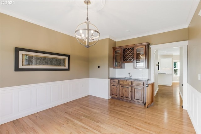 980 SW 7th St, Dundee, OR 97115 - unfurnished dining area with a chandelier, light wood-type flooring, crown molding, a wainscoted wall, and bar with sink
