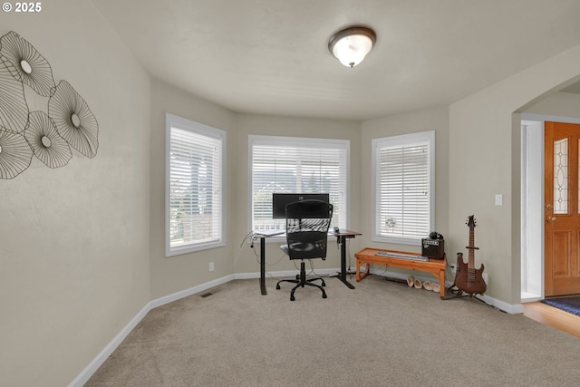 carpeted office space with arched walkways, visible vents, and baseboards