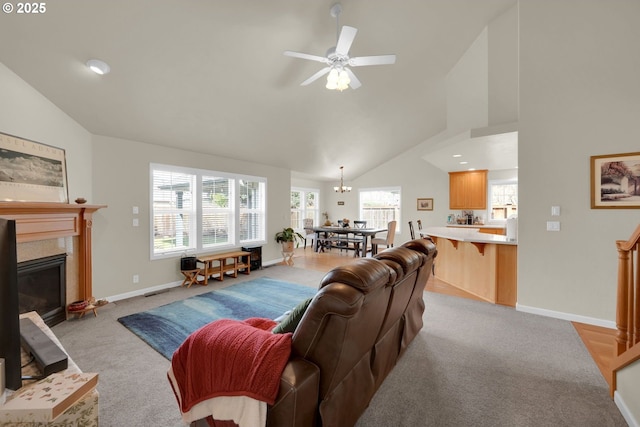 living area with light carpet, high vaulted ceiling, a tile fireplace, and baseboards