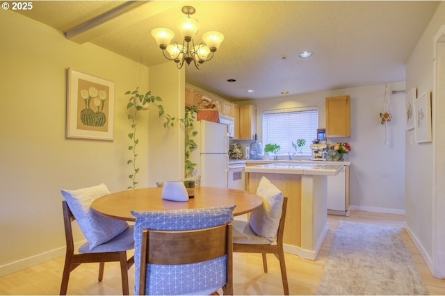 dining space with light wood-type flooring, an inviting chandelier, and a textured ceiling