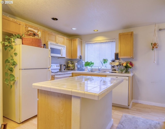 kitchen featuring light brown cabinetry, tile countertops, white appliances, a center island, and sink