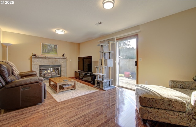 living room featuring a brick fireplace and wood-type flooring