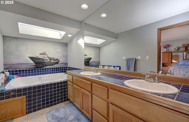 bathroom with vanity, a relaxing tiled tub, tile patterned floors, and a skylight