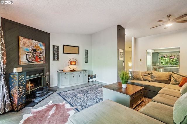 2818 Treetop Ln, West Linn, OR 97068 - living area with ceiling fan, wood finished floors, a textured ceiling, baseboards, and a large fireplace