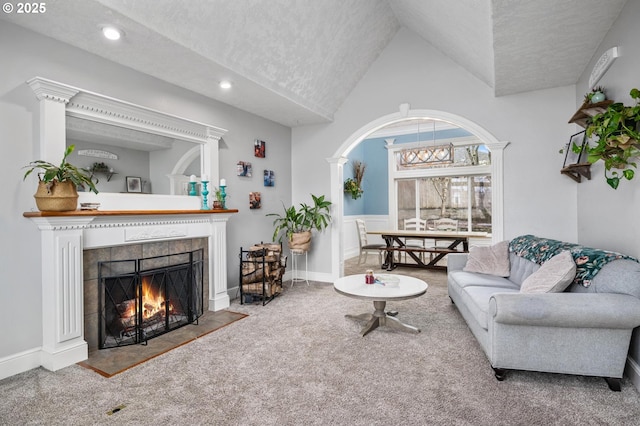 living room featuring carpet floors, a textured ceiling, a tiled fireplace, and high vaulted ceiling