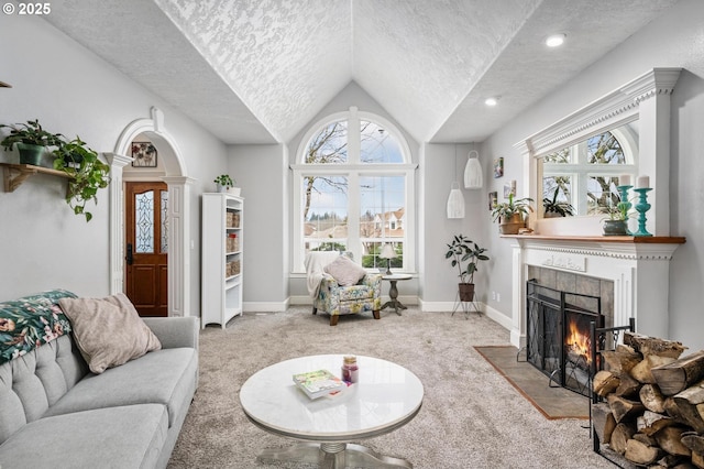 carpeted living room featuring baseboards, lofted ceiling, a textured ceiling, and a tiled fireplace