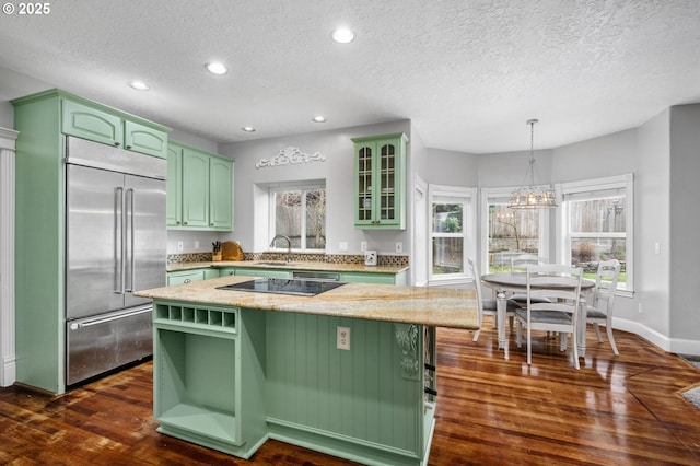 kitchen featuring green cabinetry, stainless steel built in fridge, a kitchen island, and dark wood finished floors