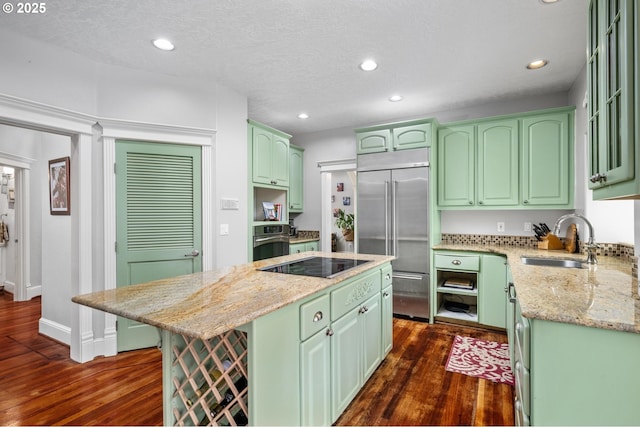 kitchen with a sink, stainless steel appliances, dark wood-type flooring, green cabinets, and a center island