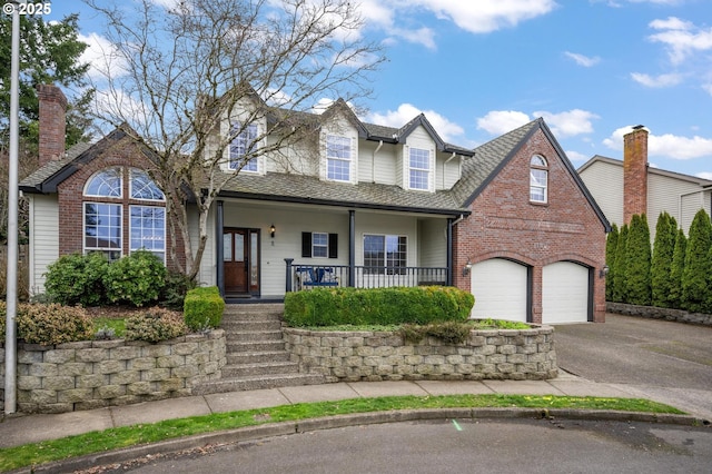 view of front of house with driveway, roof with shingles, a porch, a garage, and brick siding