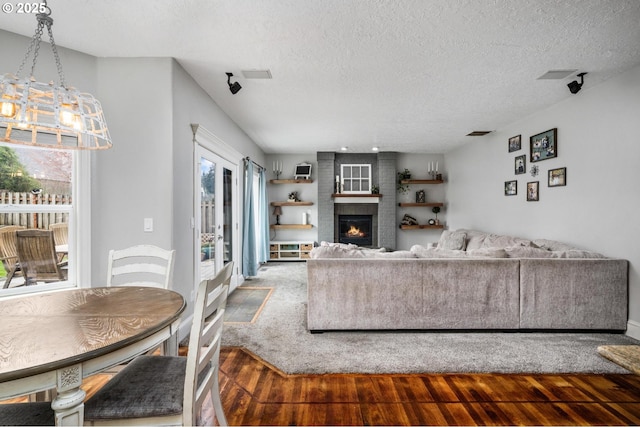 living area with visible vents, a textured ceiling, a brick fireplace, and wood finished floors