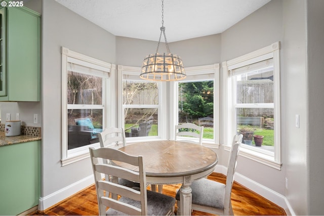 dining space with baseboards, a notable chandelier, and dark wood finished floors