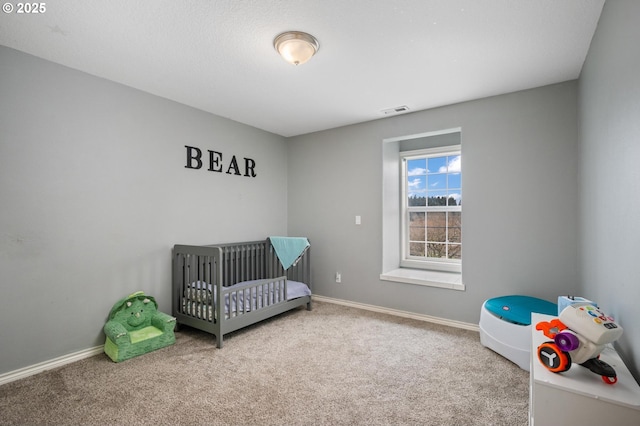 carpeted bedroom with a crib, baseboards, and visible vents