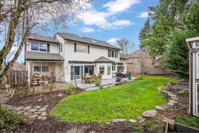 rear view of property featuring fence, roof with shingles, a yard, a garden, and a patio area