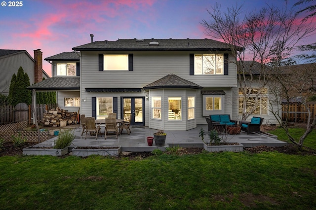 back of house at dusk featuring a patio area, a yard, and fence