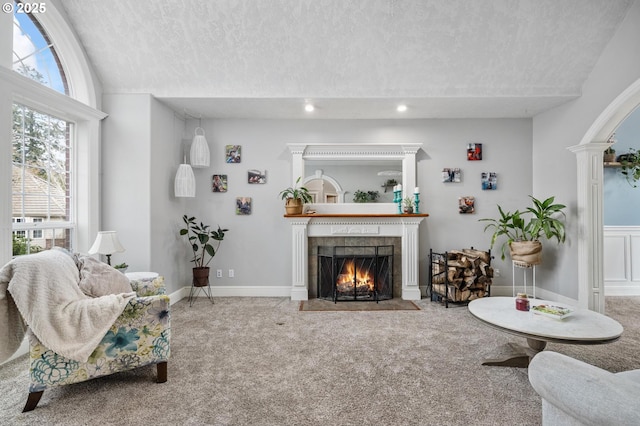 carpeted living room featuring a textured ceiling, a fireplace, vaulted ceiling, ornate columns, and recessed lighting