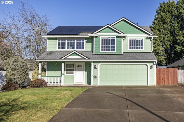 view of front of property with a porch, a garage, a front yard, and solar panels