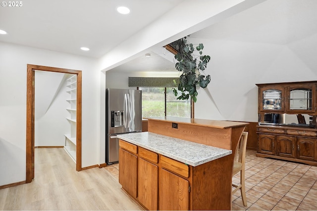 kitchen with light countertops, recessed lighting, stainless steel refrigerator with ice dispenser, light wood-type flooring, and a center island