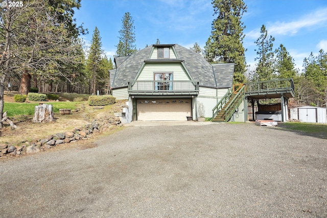 view of front of property with an outdoor structure, stairs, driveway, a garage, and a storage shed