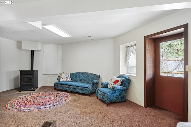 sitting room with carpet flooring, a wood stove, and visible vents