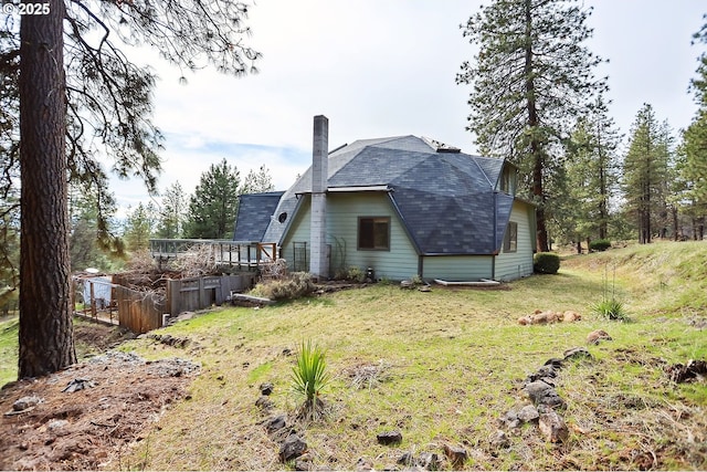 back of property with a lawn, a chimney, a gambrel roof, and a deck