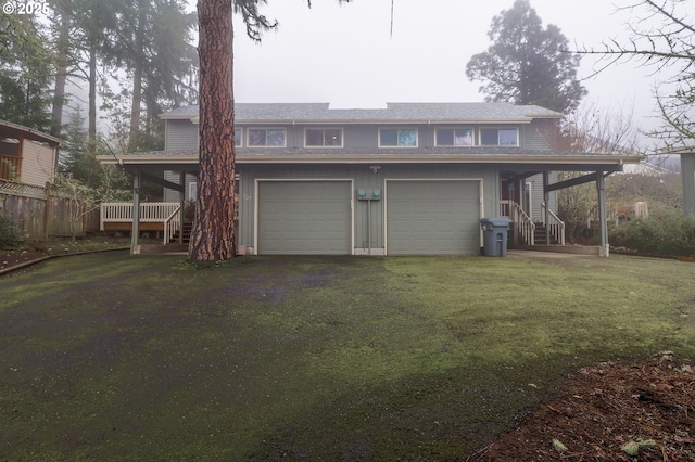 rear view of house with covered porch, a garage, and a yard