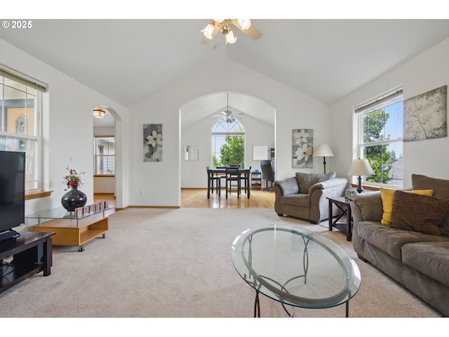 living room featuring carpet floors, arched walkways, ceiling fan, and vaulted ceiling