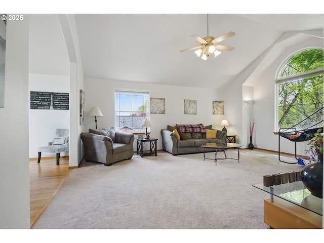 living room featuring lofted ceiling, baseboards, ceiling fan, arched walkways, and carpet flooring