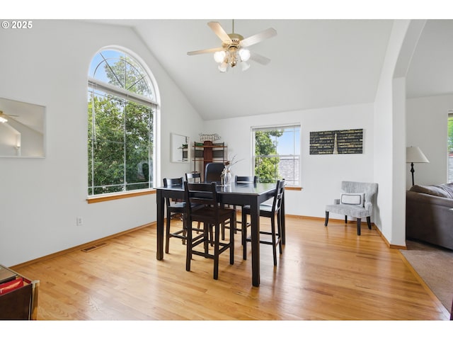 dining room with a healthy amount of sunlight, arched walkways, ceiling fan, and light wood-style floors