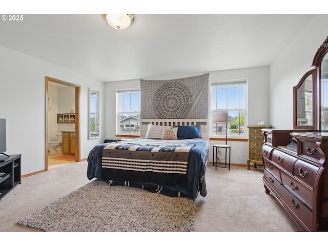 carpeted bedroom featuring baseboards, connected bathroom, and multiple windows