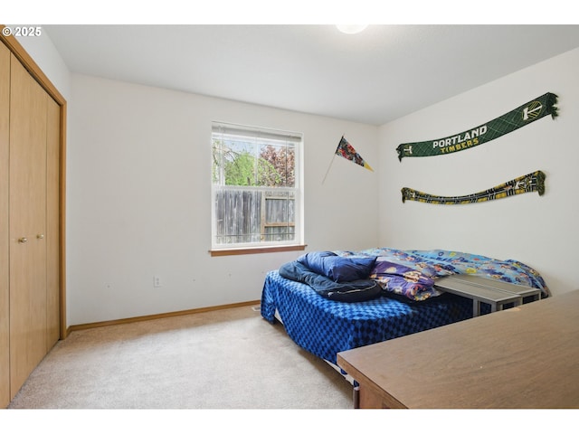 bedroom featuring baseboards, a closet, and light colored carpet
