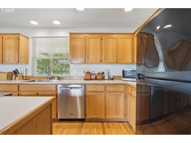 kitchen with a sink, appliances with stainless steel finishes, light wood-type flooring, and light countertops