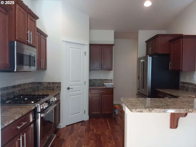 3625 Snowberry Rd, Eugene, OR 97403 - kitchen with appliances with stainless steel finishes, dark wood-style floors, a peninsula, a kitchen bar, and recessed lighting
