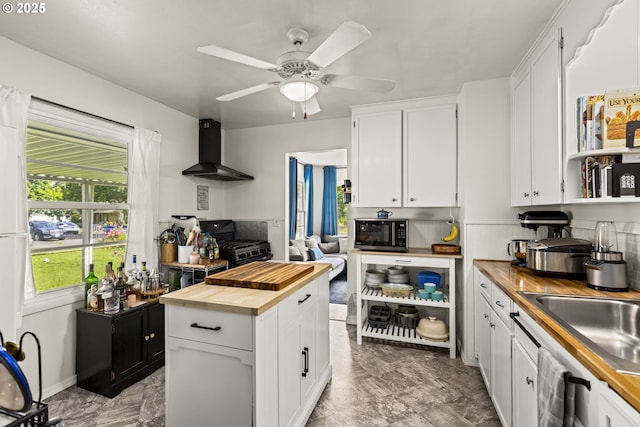 9746 SE Woodstock Blvd, Portland, OR 97266 - kitchen with butcher block countertops, wall chimney range hood, stainless steel microwave, white cabinets, and ceiling fan