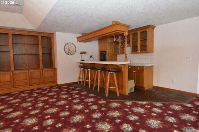 1397 State Route 506, Vader, WA 98593 - kitchen featuring glass insert cabinets, a peninsula, a kitchen bar, decorative backsplash, and brown cabinetry