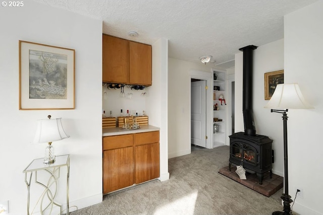 bar with light colored carpet, a textured ceiling, and a wood stove