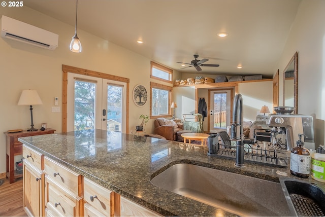 kitchen featuring an AC wall unit, light brown cabinetry, sink, hanging light fixtures, and french doors