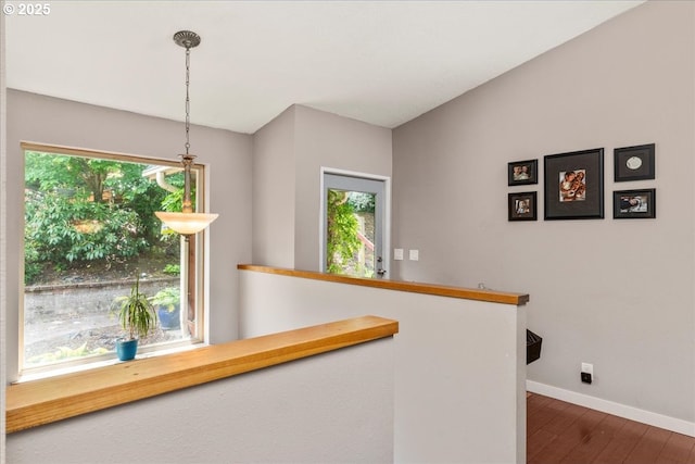 hallway featuring baseboards, an upstairs landing, and dark wood finished floors