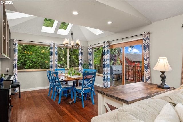 dining room with vaulted ceiling, a skylight, a chandelier, baseboards, and dark wood finished floors