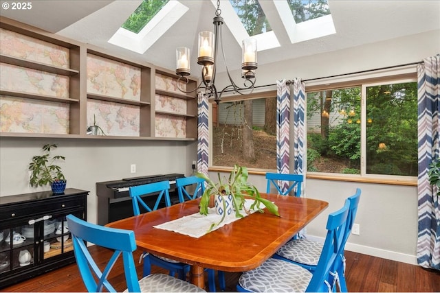 dining room featuring a skylight, wood finished floors, baseboards, and a chandelier