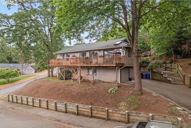 view of front of property with metal roof, a deck, stairway, and a standing seam roof