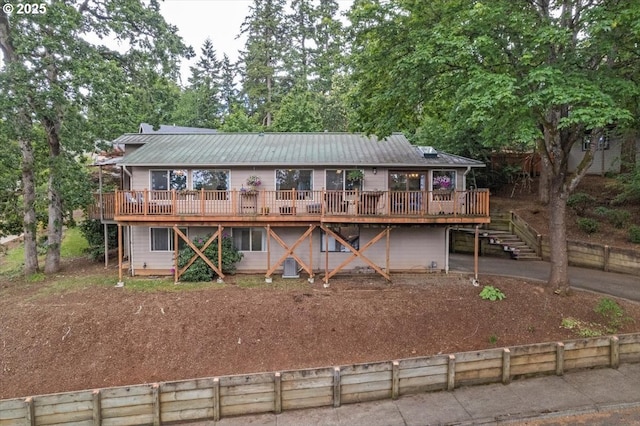 view of front facade with a wooden deck, metal roof, and stairway